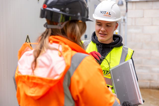 Von der Ausbildung zum Mentoring. Im Bild: Zwei junge Menschen in Arbeitskleidung und Schutzhelmen