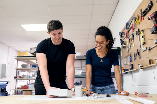 Kommunikation mit Jugendlichen in der Ausbildung. Im Bild: Zwei junge Menschen stehen gemeinsam in einer Werkstatt