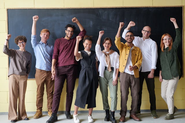 Teambuilding Power - Gemeinsam statt einsam. Im Bild: Eine Gruppe von Menschen, die nebeneinander steht und die Fäuste in die Luft streckt