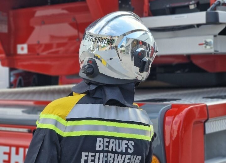 Mitarbeiter der Berufsfeuerwehr Innsbruck in Schutzkleidung vor Feuerwehrauto