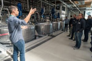 Ein Mitarbeiter der hollu Systemhygiene GmbH zeigt den Gästen das Werk