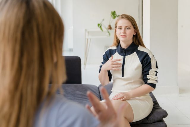 Bild von einer jungen Frau, die sich im Gespräch mit einer weiteren Person befindet