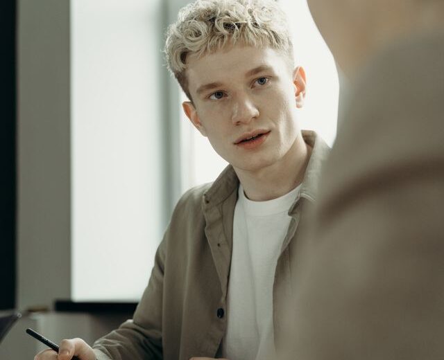 Bild eines jungen Mannes, der sich im Gespräch mit einer weiteren Person befindet
