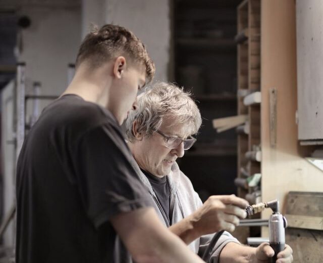 Ein junger und ein älterer mann arbeiten gemeinsam in einer Werkstatt