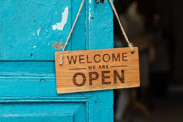 Bild eines Türschilds mit der Aufschrift "Welcome - We are open"