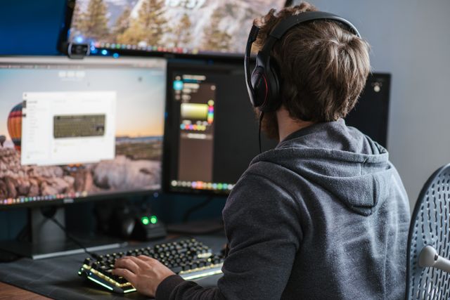 Bild von einem jungen Mann mit Headset, der vor einem Computer sitzt.
