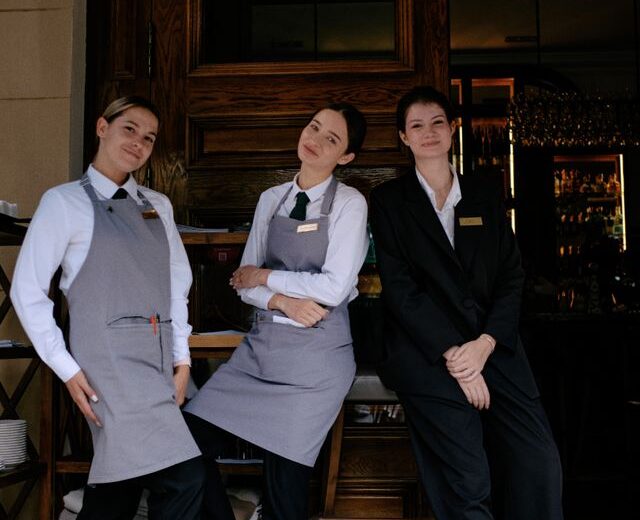 Bild von drei jungen Hotelangestellten vor einem Hoteleingang