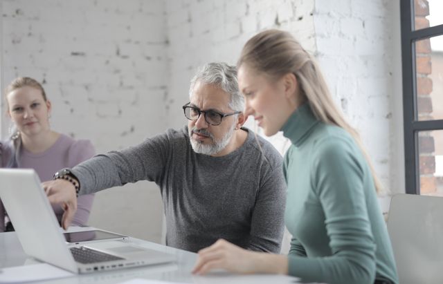 Bild einer jüngeren Frau und eines älteren Mannes, die gemeinsam an einem Laptop arbeiten